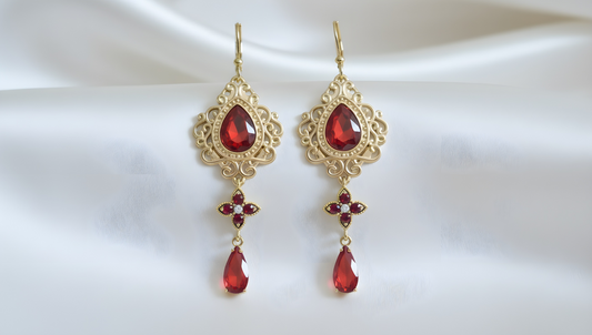 Boucles d'oreilles dorées avec pierres rouges rubis passion sur fond blanc