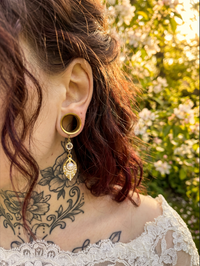 Boucles d'oreilles dorées avec perle nacrée, portées par une femme avec tatouages, ambiance naturelle, style sophistiqué, SKU: 6mm