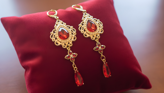 Boucles d'oreilles dorées avec pierres rouges rubis passion sur coussin rouge